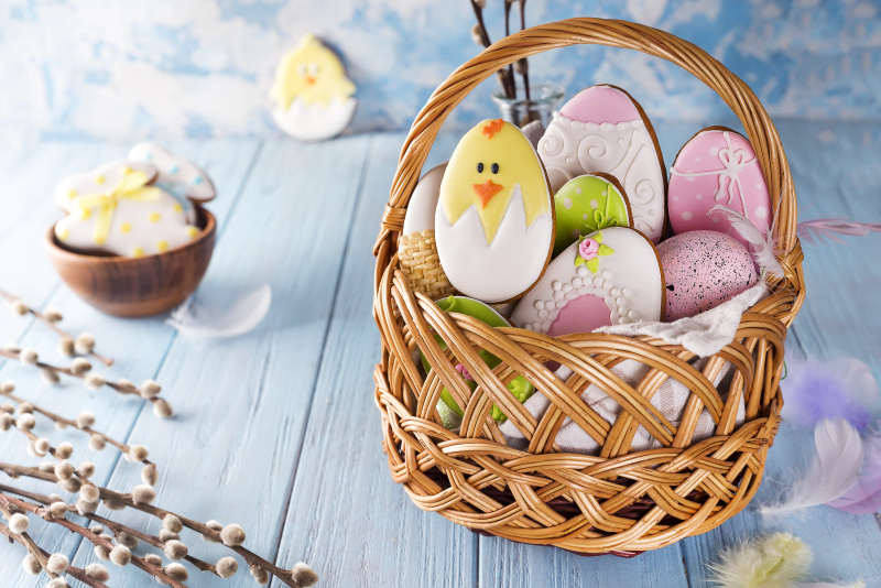 Decorated Easter Cookies in wooden basket on a blue wooden background
